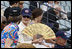 Mrs. Laura Bush wearing a U.S. Olympic baseball team hat uses a fan to keep cool as she watches the U.S. Olympic men's baseball team play a practice game against the Chinese Olympic men's baseball team Monday, Aug. 11, 2008, at the 2008 Summer Olympic Games in Beijing.