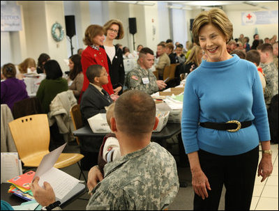 Mrs. Laura Bush greets one of the military volunteers and his child during the Saturday, Dec. 6, 2008, American Red Cross Holiday Mail for Heroes event in Washington, D.C. Standing in the background are American Red Cross President and CEO Gail McGovern, in red, and Bonnie McElveen-Hunter, Chairman of the American Red Cross. As the room full of volunteers sorted cards created by Americans to send to U.S. troops deployed around the world, Mrs. Bush encouraged Americans to do volunteer work in their home towns for those in need of food, care or appreciation. Cards for the troops can still be sent until December 10th at designated post office boxes.