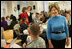 Mrs. Laura Bush greets one of the military volunteers and his child during the Saturday, Dec. 6, 2008, American Red Cross Holiday Mail for Heroes event in Washington, D.C. Standing in the background are American Red Cross President and CEO Gail McGovern, in red, and Bonnie McElveen-Hunter, Chairman of the American Red Cross. As the room full of volunteers sorted cards created by Americans to send to U.S. troops deployed around the world, Mrs. Bush encouraged Americans to do volunteer work in their home towns for those in need of food, care or appreciation. Cards for the troops can still be sent until December 10th at designated post office boxes.