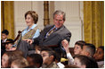 President George W. Bush, sitting with Mrs. Laura Bush, reaches to hold the hand of a young child Monday, Dec. 8, 2008 in the East Room of the White House, during the Children's Hoilday Reception and Performance.