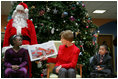 Mrs. Laura Bush reads "My Penguin Osbert" Monday, Dec. 15, 2008 to a gathering of patients and their families at Children's National Medical Center in Washington, D.C. Sitting with her are patient escort volunteers Dania Jecty, left, age 11, and Elmer Reyes, age 13.