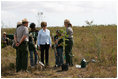 Mrs. Laura Bush joins Florida City Elementary School students Cornesha Dericho, left, and Dania Amaya, along with park ranger Allyson Gantt, right, as they prepare to plant a Gumbo Limbo tree Wednesday, Feb. 6, 2008, during the Junior Ranger "First Bloom" planting event in Everglades National Park, Fla. Mrs. Bush praised the Everglades restoration program which hopes to plant native trees to replace invasive species that are choking the park.