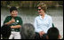 Mrs. Laura Bush smiles as a Florida City Elementary School student gives a thumbs-up while sitting on stage with Mrs. Bush, Wednesday, Feb. 6, 2008, during the Junior Ranger "First Bloom" planting event in Everglades National Park, Fla. Mrs. Bush praised the Everglades restoration program which will help bring back native trees in areas of the Everglades overgrown with non-native plants.