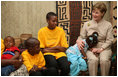 A young girl rests her head on Mrs. Laura Bush’s lap Sunday, Feb. 17, 2008, as she visits with orphans and caretakers in the Living Room of the WAMA Foundation, a non-profit organization founded by Salma Kikwete, First Lady of Tanzania.