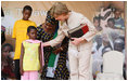 Mrs. Laura Bush pats the back of 7-year-old Zuwena Dooto, after she presented Mrs. Bush with a scrapbook during the launch of the National Plan for Action event at the WAMA Foundation Sunday, Feb. 17, 2008, in Dar es Salaam.