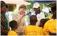 Mrs. Laura Bush waves to a child as she tours the stations of the WAMA Foundation in Dar es Salaam Sunday, Feb. 17, 2008. The Foundation is a non-profit founded by Mrs. Salma Kikwete, First Lady of Tanzania, focusing on development by improving women’s social and economic status by redefining gender roles and creating more opportunities for the development of women and children.