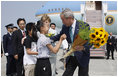 President George W. Bush and Laura Bush accept flowers from young greeters upon their arrival Sunday, July 6, 2008 to the New Chitose International Airport, to attend the Group of Eight Summit in Toyako, Japan.