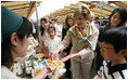 Mrs. Laura Bush tastes a sampling of the food at the Hokkaido Marche farmer's market in Makkari Village Tuesday, July 8, 2008, as part of the G-8 Spouses Program. The small village on the northern Japanese island of Hokkaido is known for its lilies and its potatoes, and the market, organized especially for the occasion of the G-8 Summit, showcased locally grown produce.