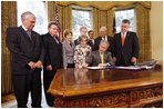 President George W. Bush signs H.J. Res. 93, the Renewal of Import Restrictions on Burma and H.R. 3890, the Tom Lantos Block Burmese JADE Act of 2008, Tuesday, July 29, 2008 in the Oval Office of the White House. President Bush was joined during the signings by, from left, Rep. Don Manzullo, R-Ill.; Rep. Chris Smith, R-N.J.; Mrs. Laura Bush, Annette Lantos, widow of Rep. Tom Lantos; Lantos grandson, Shiloh Tilleman; Rep.Rush Holt, D-N.J.; Rep. Joe Pitts, R-Pa.; and Rep. Peter King, R-N.Y.