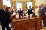 President George W. Bush signs the Caroline Pryce Walker Conquer Childhood Cancer Act of 2008 Tuesday, July 29, 2008, in the Oval Office of the White House. President Bush is joined at his desk by Mrs. Laura Bush, HHS Secretary Mike Leavitt, the Lewis family, the Adams family, the Haight family, the Rech family, and Congressional representatives Sen. Jack Reed D-RI; Minnesota Senator Norm Coleman; Rep. Deborah Pryce R-OH; and Rep. Chris Van Hollen D-MD; and CureSearch's Dr. Gregory Reaman. 