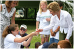 Mrs. Laura Bush takes a closer looks at a flower during a First Bloom planting event at Charlestown Navy Yard Sunday, June 22, 2008 in Boston, MA. Students of the Boys and Girls Club of Boston and Warren Prescott Elementary School participated in a three-day workshop that focused on invasive species, native plants, seed cultivation, garden design, and monitoring species.