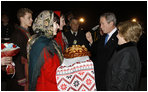 President George W. Bush acknowledges the taste of bread -- presented as a traditional Ukrainian welcome -- as he and Mrs. Laura Bush are greeted upon their arrival Monday, March 31, 2008, at Boryspil State International Airport in Kyiv.