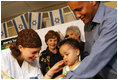 Mrs. Laura Bush looks on during an examination of 1-year-old Orie Holkan during a visit Wednesday, May 14, 2008, to the Tipat Chalav-Gonenim Neighborhood Mother and Child Care Center in Jerusalem. With them are Ms. Sarit Fuast, the nurse, and Talala Holkan, the young child's father.