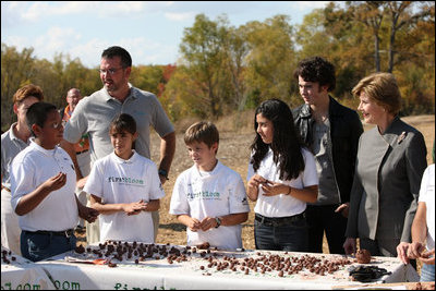 Mrs. Laura Bush listens as a child tells her about making seed balls speaks during a First Bloom Event at Trinity River Audubon Center, Sunday, November 2, 2008 in Dallas, TX. Mrs. Bush is joined by Benjamin Jones, Director of Education, Trinity River Audubon Center, left and singer/songwriter Kevin Jonas of the Jonas Brothers, right.