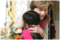 Mrs. Laura Bush hugs a young girl after she was presented with a bouquet of flowers upon her arrival welcome to the San Clemente Health Center Friday, Nov. 21, 2008, in San Clemente, Peru. Mrs. Bush visited the center and participated in interactive demonstrations depicting community-based health training.