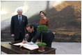 Italian Prime Minister Silvio Berlusconi follows Mrs. Laura Bush in signing the guest book Oct. 13, 2008 at the National Gallery of Art in Washington At left is Mr. Rusty Powell, Director of the National Gallery of Art, who led a tour of the exhibit "Pompeii and the Roman Villa; Art and Culture Around the Bay of Naples." The Mt. Vesuvius mural one of the backdrops for the exhibit.