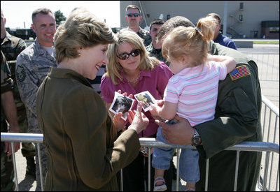 Mrs. Laura Bush offers photos of the Bush family dogs, Scottish Terrier's Barney and Mrs. Beazley, and the cat, Willie, to a little girl before departing from Forbes Field in Topeka, Kan., on Tuesday, Sept. 16, 2008. She had just greeted members of the military gathered to see her departure from the air field.