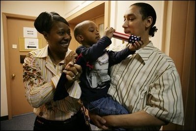 Kevion Thigpen, 3, held by his parents Kanyatta "Ken" Thigpen and his girlfriend Jewell Reed plays with a kaleidescope given to him by Laura Bush during a visit to the Rosalie Manor Community and Family Services center in Milwaukee, Wis., Tuesday, March 8, 2005. Citing a New York Times article by Jason DeParle Mrs. Bush credits Mr. Thigpen's determination to be a responsible father with bringing her attention to the needs of boys and young men.