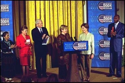 Laura Bush welcomes Ludmila Putina, wife of Vladimir Putin, President of the Russian Federation, to the Second Annual National Book Festival Saturday, October 12, 2002 in the East Room of the White House. Standing with the first ladies on stage are, left to right, Native American poet Lucy Tapahoso, writer Mary Higgins Clark, Librarian of Congress James Billington, and NBA player Jerry Stackhouse. White House photo by Susan Sterner.