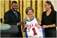 Golden State Warrior Baron Davis, left, and Phoenix Mercury guard Diana Taurasi, right, present Laura Bush with a basketball jersey at the National Book Festival Author's breakfast in the East Room Saturday, Sept. 24, 2005. 