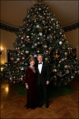 Celebrating the 2007 holiday season, President George W. Bush and Mrs. Laura Bush pose in front of the Christmas Tree in the Blue Room of the White House.