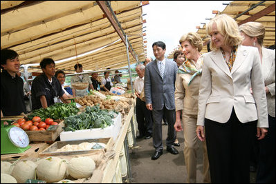 Mrs. Laura Bush joins spouses of the G8 leaders as they visit the Hokkaido Marche (northern farm market), in Makkari Village Tuesday, July 8, 2008. The Hokkaido Marche was especially organized by the local residents on the occasion of the Summit, with the aim of illustrating the richness of locally produced foods. In the foreground is Mrs. Laureen Harper, wife of the Prime Minister of Canada.