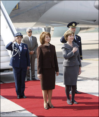 Mrs. Laura Bush holds her hand over her heart during the playing of the national anthem Wednesday, April 2, 2008, as she stands with Mrs. Maria Basescu, spouse of Romania's President Traian Basescu, on the red carpet during the arrival ceremony at Mihail Kogalniceanu Airport in Constanta, Romania.