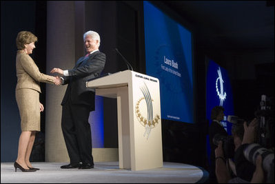 Mrs. Laura Bush is welcomed to the podium by former President Bill Clinton Wednesday, September 20, 2006, at President Clinton's Annual Global Initiative Conference in New York. During her remarks, Mrs. Bush announced a $60 million public-private partnership between the U.S. Government and the Case Foundation to provide clean water for up to 10 million people in sub-Sahara Africa by 2010. The partnership will support the provision and installation of PlayPump water systems in approximately 650 schools, health centers and HIV affected communities. White House photo by Shealah Craighead 