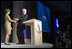 Mrs. Laura Bush is welcomed to the podium by former President Bill Clinton Wednesday, September 20, 2006, at President Clinton's Annual Global Initiative Conference in New York. During her remarks, Mrs. Bush announced a $60 million public-private partnership between the U.S. Government and the Case Foundation to provide clean water for up to 10 million people in sub-Sahara Africa by 2010. The partnership will support the provision and installation of PlayPump water systems in approximately 650 schools, health centers and HIV affected communities. White House photo by Shealah Craighead 