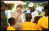 Mrs. Laura Bush waves to a child as she tours the stations of the WAMA Foundation in Dar es Salaam Sunday, Feb. 17, 2008. The Foundation is a non-profit founded by Mrs. Salma Kikwete, First Lady of Tanzania, focusing on development by improving women’s social and economic status by redefining gender roles and creating more opportunities for the development of women and children.