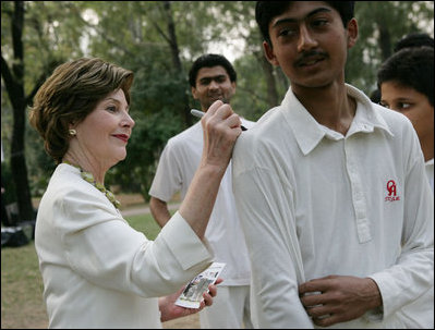 Mrs. Laura Bush signs the team jerseys of the Islamabad College of Boys cricket team, who participated in a cricket clinic with President George W. Bush, Saturday, March 4, 2006 at the Raphel Memorial Gardens on the grounds of the U.S. Embassy in Islamabad, Pakistan.