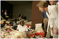 Laura Bush leans down to comfort a woman and her young child inside the Cajundome at the University of Louisiana in Lafayette during her visit to the center, one of many created to accommodate victims of Hurricane Katrina.