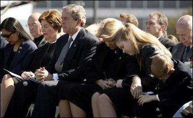 Joining the family of Space Shuttle Columbia Commander Rick Husband, President George W. Bush and Laura Bush bow their heads in prayer during a memorial service at NASA's Lyndon B. Johnson Space Center Tuesday, Feb. 4, 2003. Sitting with the President are Mr. Husband's wife, Evelyn, and children Laura and Matthew. White House photo by Paul Morse.