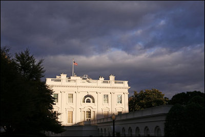 Signaling the fast approaching Autumnal Equinox, a blue sky is crowded with thick clouds as a brisk North wind ripples through the American flag flying over the White House.