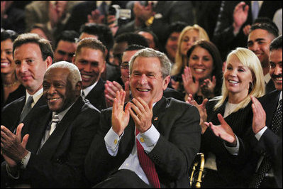 President George W. Bush applauds during the Celebration of Hispanic Heritage Month in the East Room, Thursday, Oct 2, 2003. Also pictured from left are, Tony Garza, U.S. Ambassador to Mexico and Pedro Knight, the husband of late singer Celia Cruz.