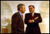 Before taking a photo with Hispanic members of his staff as part of the Cinco de Mayo celebrations, President George W. Bush speaks with Secretary for Housing and Urban Development Mel Martinez in the downstairs corridor May 3, 2002. 