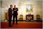 Before taking a photo with Hispanic members of his staff as part of the Cinco de Mayo celebrations, President George W. Bush speaks with Secretary for Housing and Urban Development Mel Martinez in the downstairs corridor May 3, 2002.