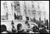 President Hoover waves to crowds at the 1929 Easter Egg Roll from the balcony of The White House. First Lady Lou Hoover, who introduced maypole and folk dancing activities to the event, smiles beside him. 