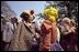 Mrs. Ford greets a clown at the 1976 White House Easter Egg Roll while President Ford watches in the background.