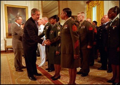 With a portrait of America's first General and first President hanging in the background, President George W. Bush and Defense Secretary Donald Rumsfeld congratulate military re-enlistees in an event held in the East Room May 23, 2001. Congress purchased the portrait of George Washington by Gilbert Stuart for the White House in 1800.