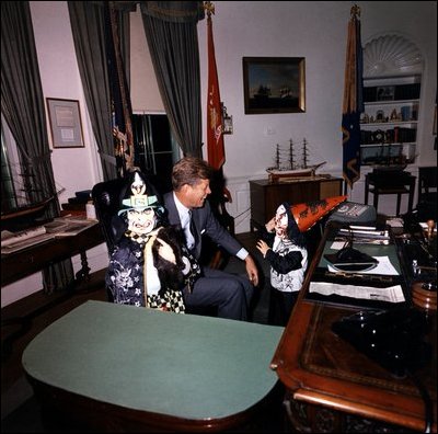 President John Kennedy meets with his halloween-clad children, Caroline and John, Jr., in the Oval Office. 