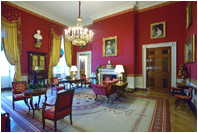 The Red Room is decorated with garlands and topiaries made of pomegranates, pears and magnolia leaves. A small cranberry tree surrounded by holly sits on an antique marble-top table.