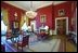 The Red Room is decorated with garlands and topiaries made of pomegranates, pears and magnolia leaves. A small cranberry tree surrounded by holly sits on an antique marble-top table.