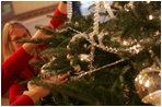 Decorators place holiday trimmings on the White House Christmas Tree, a large Fraser Fir, in the Blue Room of the White House, Monday, Nov. 28, 2005.