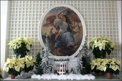 Poinsettias stand with a model of the White House in the Palm Room located near the Rose Garden.