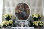 Poinsettias stand with a model of the White House in the Palm Room located near the Rose Garden.