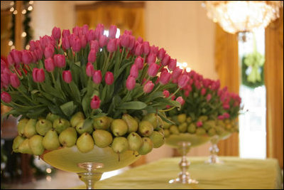 Hot pink tulips and green pears stand in line on the center table of the East Room.