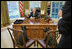 President Bush discusses the true meaning of the holidays with Barney and Miss Beazley in the Oval Office.