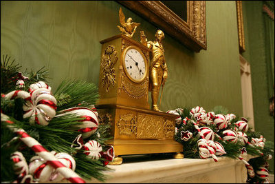 Red and white peppermint swirled candies accent the garland on the fireplace mantle in the Green Room.