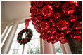 Festive wreaths are hung in each of the windows along the East Colonnade, where red ornament balls create bold tree-like sculptures.